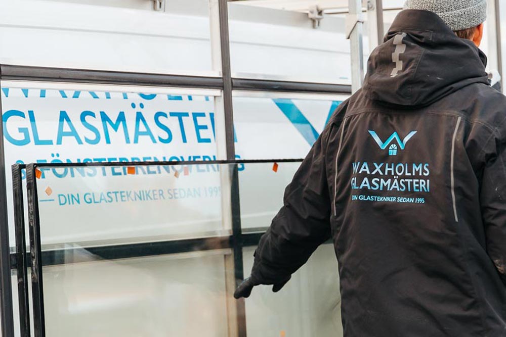 Medarbetare på Vaxholms glasmästeri som håller i ett fönster